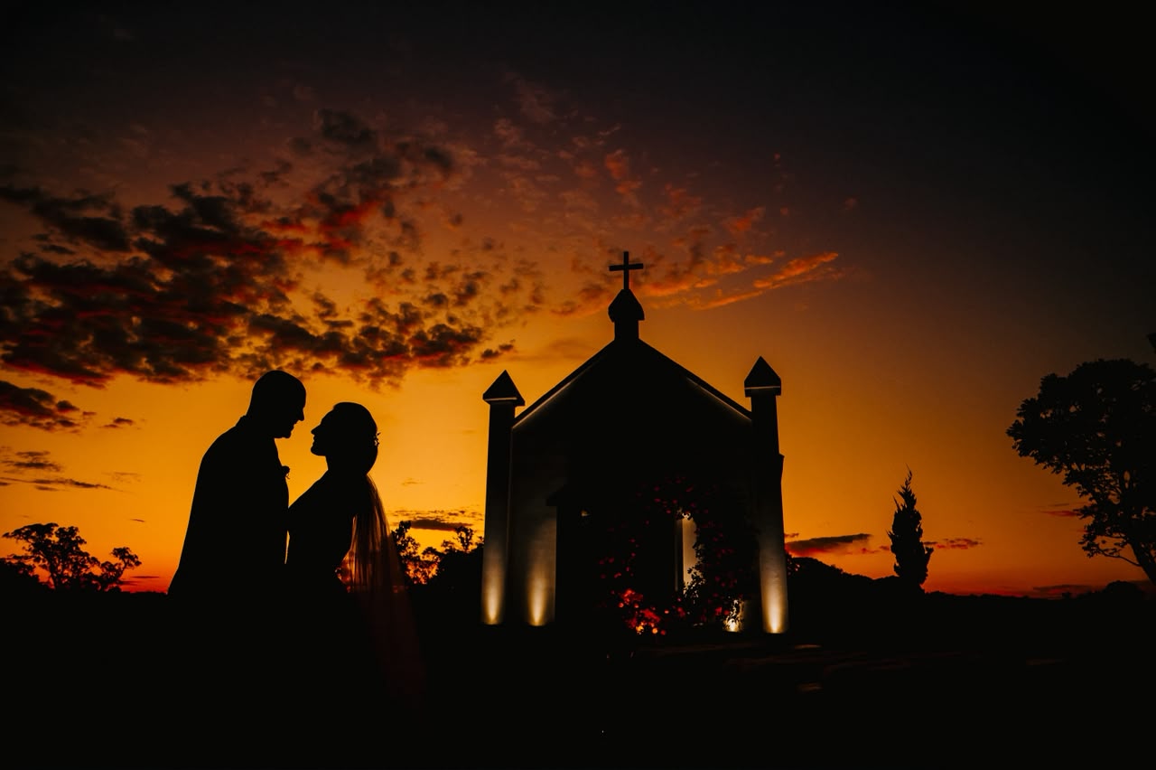 Silhueta dos noivos na capela ao pôr do sol